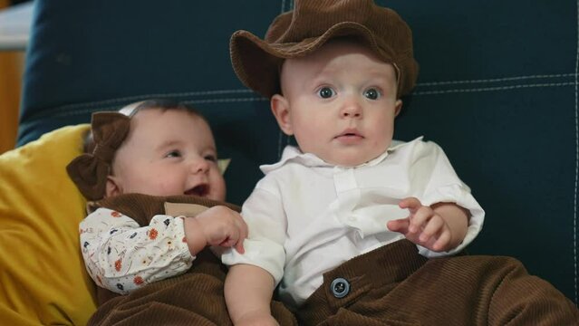 twin babies in retro clothes. brother and sister a twins kids sit on the couch in retro clothes cap play among themselves. happy family kid dream lifestyle twin concept