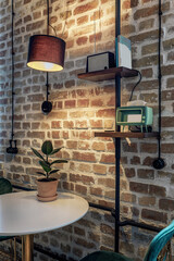 Stylish brick wall in retro style with a table standing next to it, illuminated by a lamp
