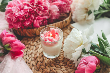 Cozy spring composition, burning candle, peonies and hat.
