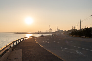 Fototapeta na wymiar Sunrise on the coastal road with container cranes visible 