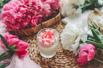 Fototapeta na wymiar Cozy spring composition, burning candle, peonies and hat.