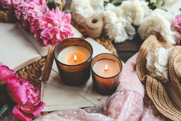 Two burning candles and pink peonies, spring atmosphere