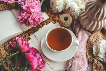 Beautiful spring composition, good morning concept. Cup of tea, peonies and open book