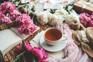 Beautiful spring composition, good morning concept. Cup of tea, peonies and open book