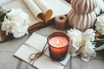 Burning candle and white peonies, vintage aesthetic