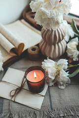 Burning candle and white peonies, vintage aesthetic