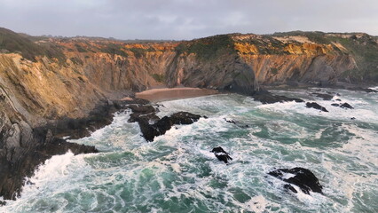 Aerial footage of the cliffs and beach in Portugal. Rota Vicentina. Slow motion ocean