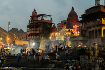 India Varanasi ganga ghat at night, view of the crowded banks of people and funeral pyres - obrazy, fototapety, plakaty