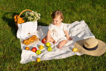 little baby on picnic with flowers and fruits in the summer park, sunny day