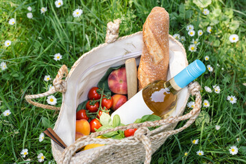 Bottle of white wine and fresh fruit in a picnic bag.