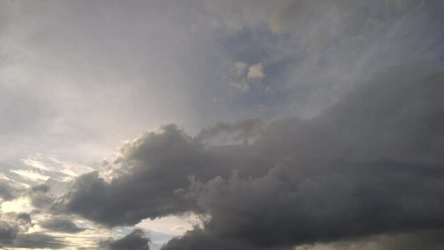 Huge cumulus clouds being illuminated by the golden light of sunset move across the sky
