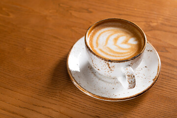 Hot coffee cup with foam on a wooden table in cafe - 613534978