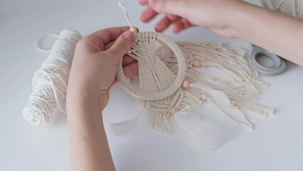 Macrame. The girl weaves macrame. White thread, female hand, close-up