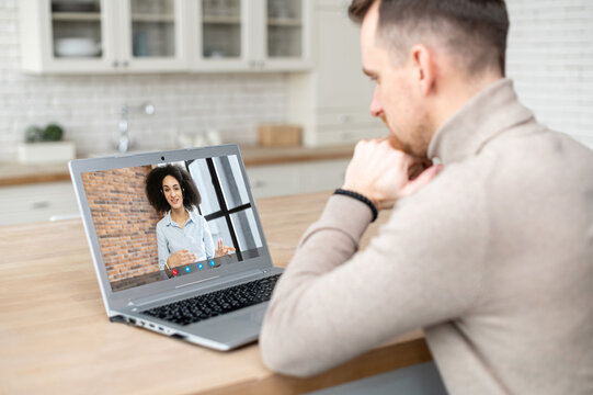 Video call concept. Young man is talking online with an African woman, female coworker, chatting with a support officer