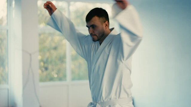 Martial art school student In white kimono warming up before training, sparring 