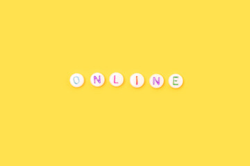 Online. Quote made of white round beads with colorful letters on a yellow background.