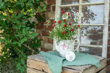 Natürlicher Blumenstrauß in alter Kaffeekanne, rustikale Tischdekoration, frische Blumen, roter...