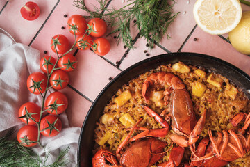 spanish seafood paella with lobster and squid, traditional dish with rice, top view of a hot pot,...