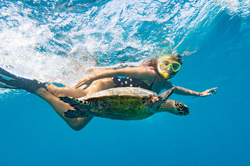 Snorkeling with a sea turtle. Girl swimming with a mask next to the turtle, Maldives