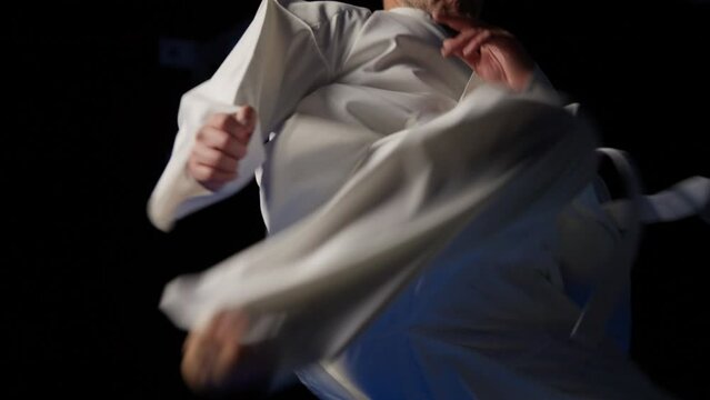 Taekwondo master demonstrating spinning kick on black background, combat sport