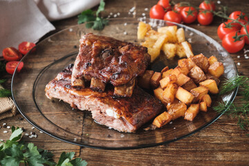 grilled ribs with vegetables, baked potatoes and pineapple on a glass plate, wooden table, top view, fresh ingredients around
