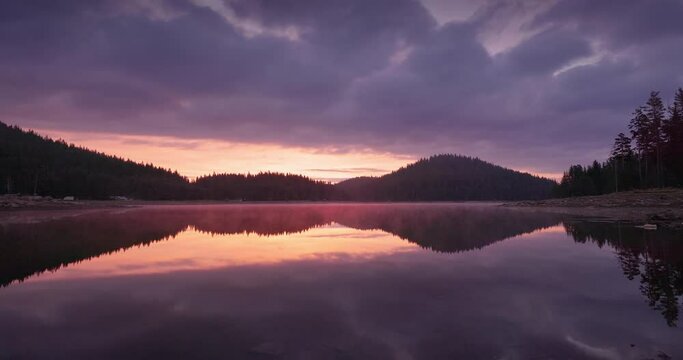 Color cinematic sunrise over lake water and green forest pine trees. Nature panorama landscape with dam Shiroka polyana (Wide meadow) Rodopi mountain. Bulgaria