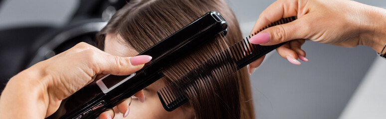beauty profession, straightening hair, hairdresser brushing and styling short brunette hair of...
