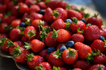 Juicy berries of red strawberries and blueberries, top view. Background of a mixture of fragrant fresh summer berries. Red and black berries. Healthy lifestyle concept, selective focus