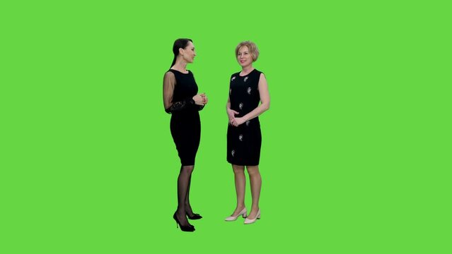 Meeting of two elegant women in black dresses and their communication on green background, Chroma key, 4k pre-keyed footage
