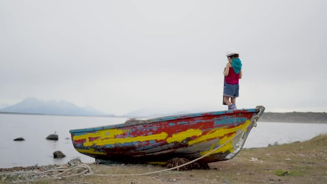 Little girl playing on a red fish boat like a young captain looking at the sea. Game, imagination, creativity. High quality FullHD footage