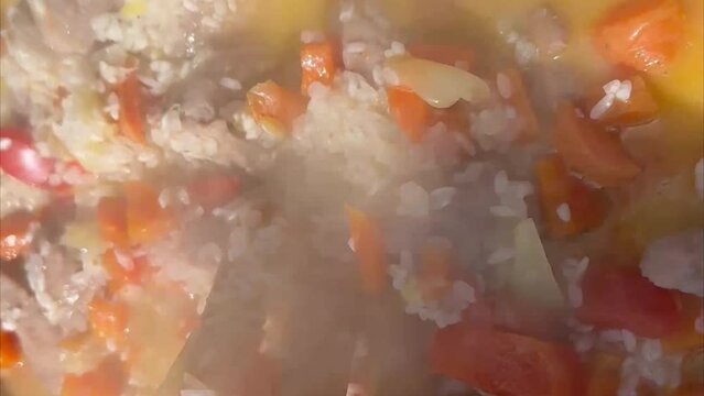 pilaf. rice with meat is cooked in a cauldron close-up. healthy food asian cuisine concept. pilaf rice with meat and carrots in the smoke cooking on a fire lifestyle