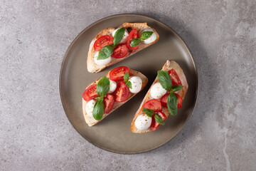 Tomato, basil and cheese fresh made caprese bruschetta. Italian tapas, antipasti with vegetables, herbs and oil on grilled ciabatta and baguette bread. Sandwich.