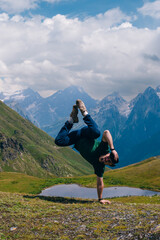 A man traveler breake dance, dancing near the Koruldi Lake, Mestia in the Greater Caucasus Mountain Range Upper Svaneti, Georgia. travel and vacation. Summer day. Vertical photo