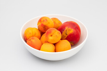 Few biologic nectarina, apricots on white bowl
