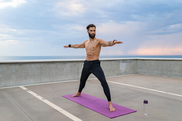 attractive hansome man with athletic strong body doing morning yoga asana outdoors