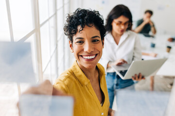 Happy business woman writing ideas on sticky notes in an office