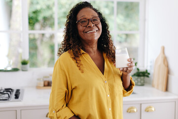 Mature black woman having a glass of fresh milk for breakfast