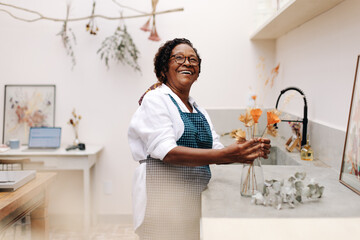 Happy senior woman arranging dried floral craft into a bouquet