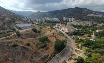 Fototapeta na wymiar View of the road and the city in the distance from a height in Israel 2023 mountains and a leaden sky behind the houses