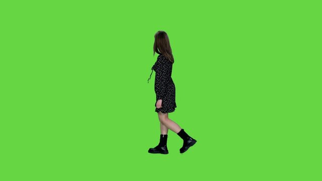 Back view young woman in short polka dot dress watching at something on green background, Chroma key, 4k pre-keyed footage