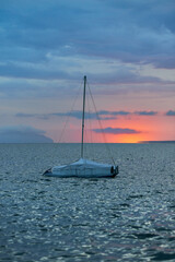 a sailboat moored at the Stagnone of Marsala in front of the Egadi islands at sunset and sky with dense blue clouds