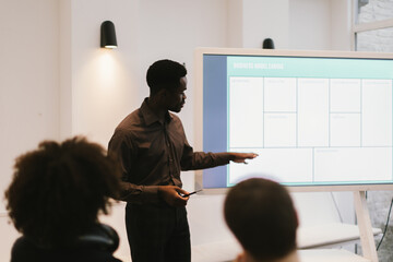 black professional man giving workshop using digital slides on screen