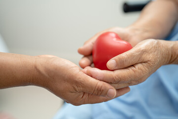Asian senior holding a red heart in hospital, healthy strong medical concept.