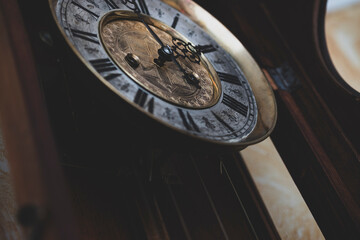 Old wooden clock with a pendulum hanging on the wall