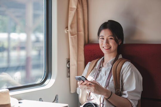 Beautiful girl takes picture of landscape with her smartphone sitting on train