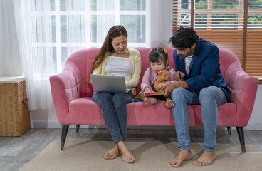 interracial couple and little daughter enjoy their free time in the living room together, happy family,husband, wife and little child resting on holiday. concept for family, lifestyle,relationship
