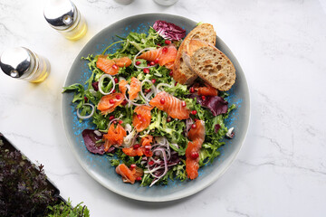 Salad with smoked salmon, onion and pomegranate seeds, served with bread. Healthy lunch with fish, top view.