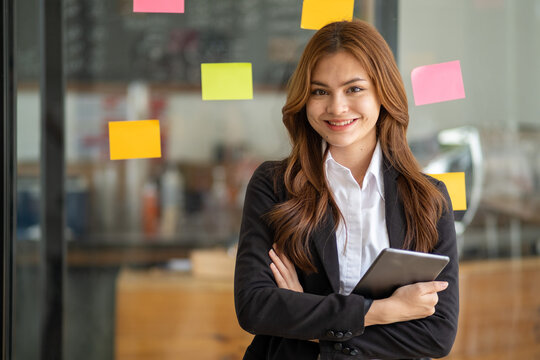 Happy businesswoman planning ideas project work on a glass of wall with colorful memo