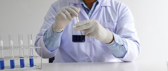 Science innovative Male medical or scientific laboratory researcher performs tests with blue liquid...