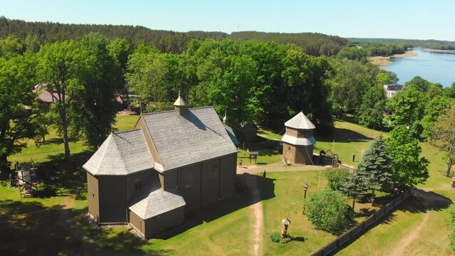 Aerial view Young lithuanians relax on sunday mass by St. Joseph Church in Paluse, Lithuania. Stave Churches in Europe. Old heritage sites. Walls formed by vertical wooden boards.